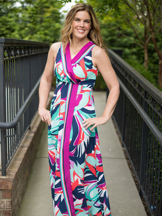 a sleeveless wrap dress in navy teal with maxi length featuring abstract floral patterns and contrasting lined border print