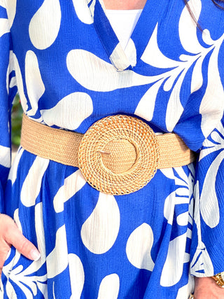 natural colored basket weave straw belt with large circle buckle worn on a blue dress