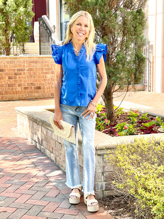 vibrant royal blue top with ruffled details and double flutter short sleeves paired with faded blue jeans