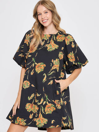 black mini dress with orange floral print and short puff sleeves with pockets
