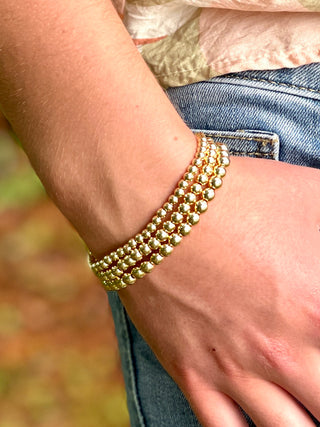 a group of three gold beaded bracelets in different sizes