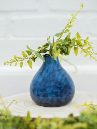 a deep blue vase with black marbling shown with faux foliage