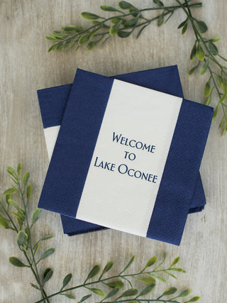 a pack of white and dark blue cocktail napkins that read welcome to lake oconee
