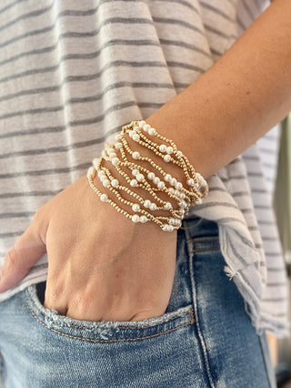 a bright stack of gold and pearl bracelets