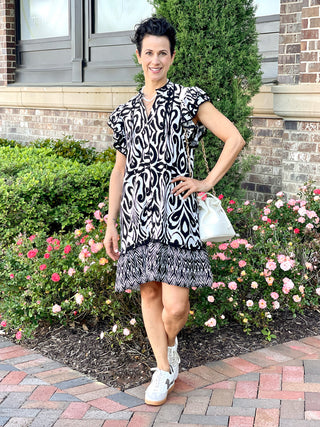 black and white print mini dress with ruffled short sleeves and button down front worn with white sneakers