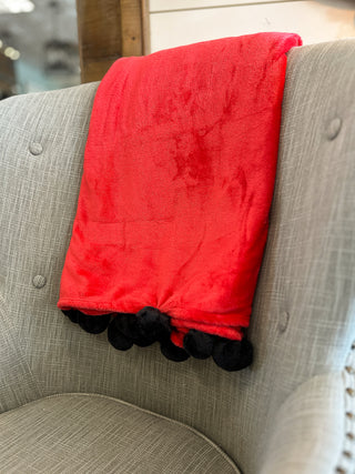 a black and red throw blanket with soft pom poms along the edge perfect for uga bulldogs football game days at home