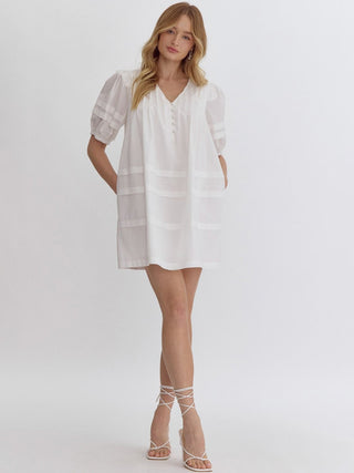coastal vibe off white puffy sleeved mini dress with tiered design and side pockets worn with white sandals