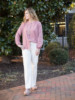 a dark pink linen button down blouse with long elastic cuffed sleeves with cream wide leg pants