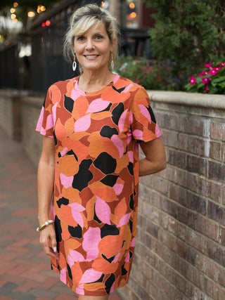 a patterned short sleeve dress with orange and pink accents featuring an open back
