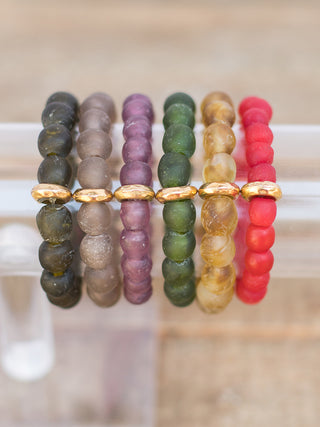 a collection of stacked sea glass bracelets in multicolor beads with gold details