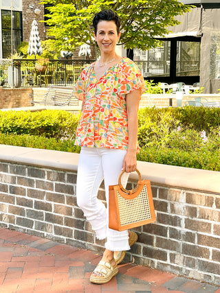 a relaxed fit short sleeve top with a vibrant orange print worn with white pants