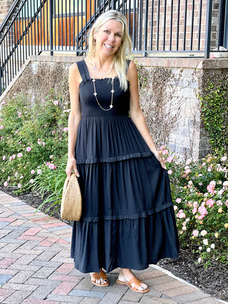 a black sleeveless midi sundress with square neckline and lightweight tiers worn with brown sandals