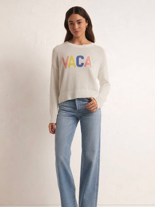 white crew neck vacay pullover sweater with multicolor letters paired with light blue jeans