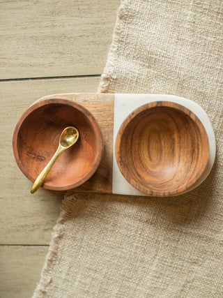 a modern food safe set featuring an acacia wood and marble tray with 2 acacia bowls and a brass spoon
