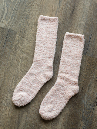 a pair of fuzzy socks in pale pink
