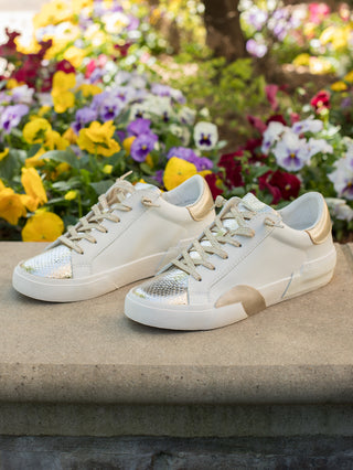 a pair of lowtop sneakers with white and gold metallics and a snake skin pattern