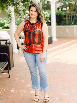 a red and black sequin football jersey style tank perfect for uga bulldogs fans and game days shown with fringe denim pants