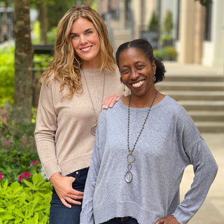 two women in matching sweaters in a friendly embrace