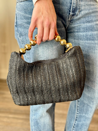 a stylish black mini bag with a gold bubble handle