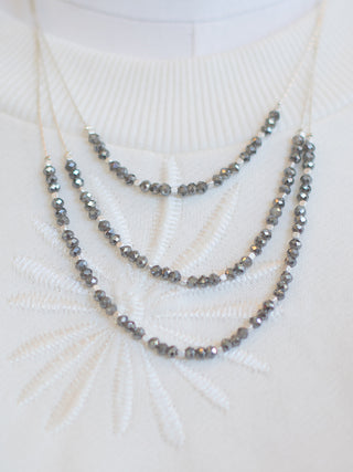 wear this gold layered necklace with metallic hematite stones as a sparkly accessory to brighten winter outfits