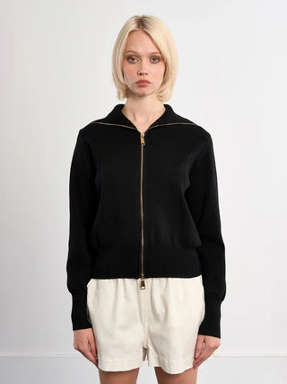 Person wearing a black zip-up sweatshirt and white shorts on a light gray background