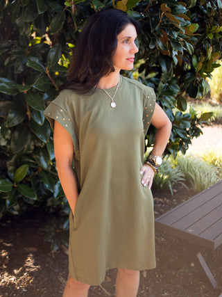 a dark green shift dress with brass studs along the short sleeves and pockets perfect for summer to fall fashion
