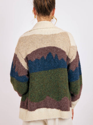 a soft long sleeve collared cardigan with a western alpine landscape pattern worn over a brown top