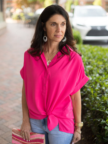 a hot pink half button up blouse with short sleeves and a tie at the hem
