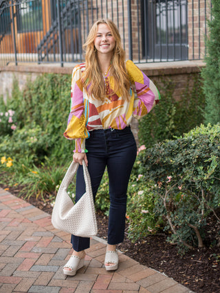 a multicolor geometric blouse in purple and yellow in lightweight fabric with statement sleeves shown with white platforms