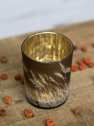 a gold bronze candle votive with white reeds printed along the side perfect for fall home decor