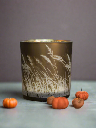 a gold bronze candle votive with waving grass in white along the sides perfect for fall home decor