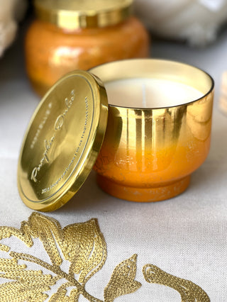 a shiny orange and gold pumpkin dulce candle with notes of autumn and a gold lid