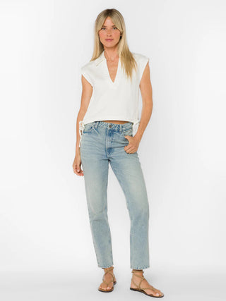 Woman wearing a white sleeveless top and light blue jeans on a white background