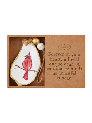 a sentimental box with a holiday cardinal ornament on a white oyster shell with gold beads