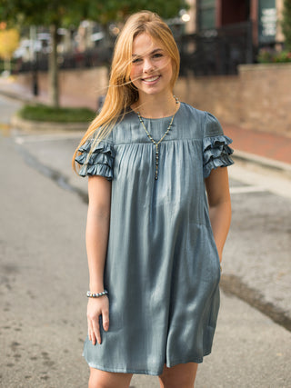 a satin steel blue dress with ruffles on the short sleeves and a mini hemline perfect for glamorous dressing