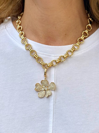 a shiny gold twisted link chain necklace with double connectors and a flower charm attached