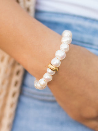 a pearl stretch bracelet in ivory with a string of exquisite pearls and a gold washer charm