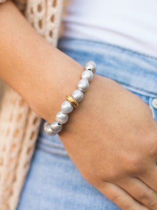 a pearl stretch bracelet in silver with a string of exquisite pearls and a gold washer charm