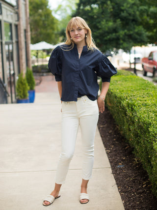 a dramatic button up blouse with statement sleeves in navy perfect for day to night looks shown with white pants