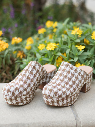 a pair of houndstooth print platform clogs in brown and cream that harken to nineties trends