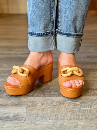 a pair of tan leather open toe clog sandals with a chic wooden chain link