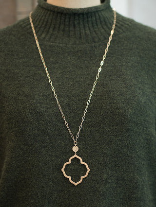 a long gold necklace with a decorative pendant perfect for necklace layering and to wear with deep v neck silhouettes