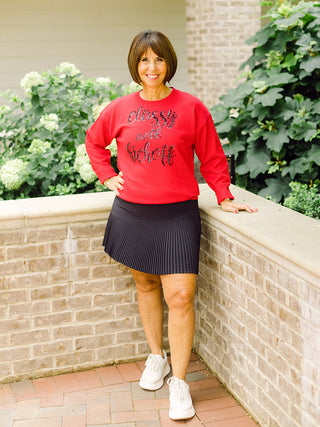 a red sweater with black lettering that reads classy until kickoff for game day shown with a black tennis skirt