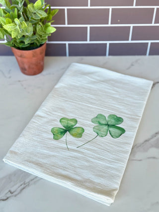 a white tea towel with pair of green clovers