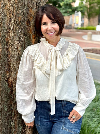cream blouse with long sleeves and ruffled details with front tie
