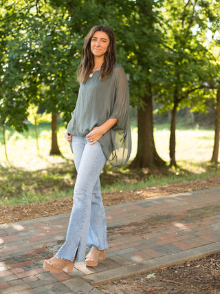 a sea grey italian silk blouse with semi sheer sleeves and a flowing fit great for summer to fall fashion shown with denim
