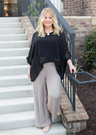 a black italian silk blouse with semi sheer sleeves and a flowing fit great for summer to fall fashion shown with silk pants 