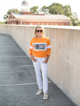 a tennessee sweatshirt with orange and white color block perfect for fall football games and vols pride shown with white pants