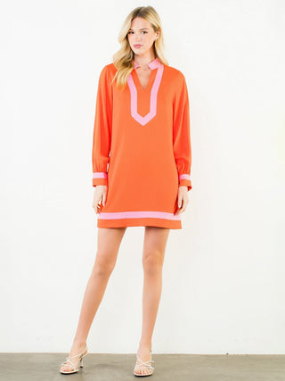 a vibrant tropical orange and pink long sleeve mini dress worn with white sandals