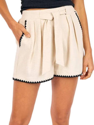 relaxed cream shorts with black embroidered sides and a big waist tie with pockets